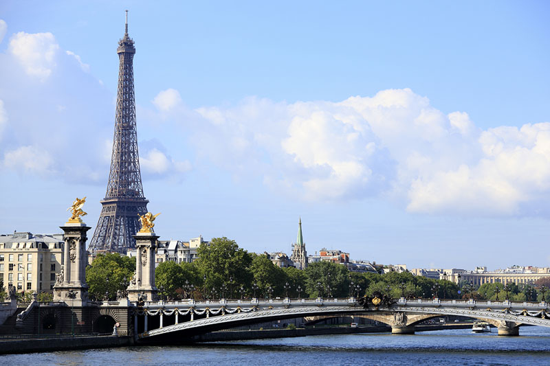Paris scene with River Seine, Pont Alexandre III and skyline with Eiffel Tower in the distance.